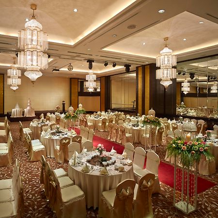 Parkroyal Penang Resort Batu Ferringhi Exterior photo The photo shows an elegant banquet hall set up for an event. The room features several round tables, each adorned with white tablecloths and decorative centerpieces. The chairs are mostly covered in gold fabric, adding a touch of sophistication. The 