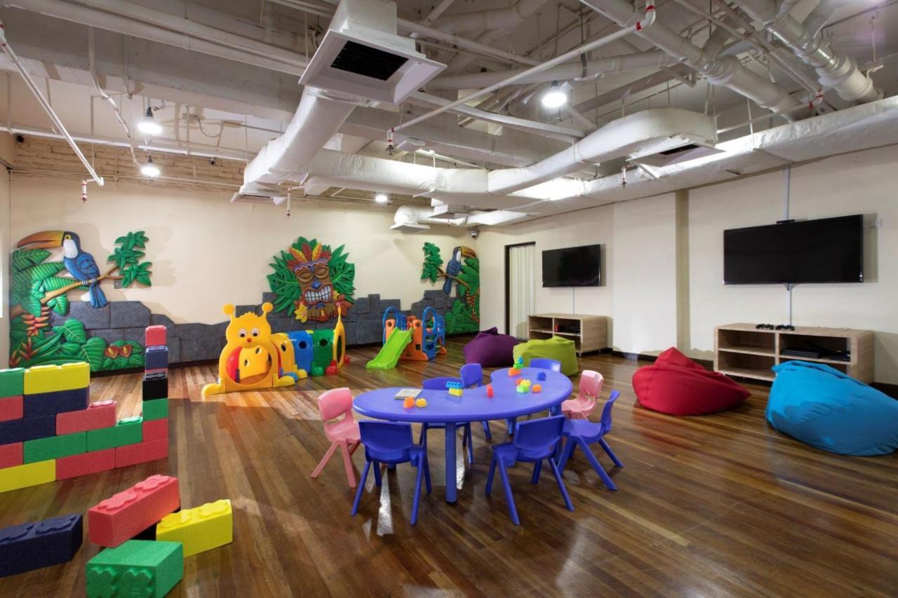 Parkroyal Penang Resort Batu Ferringhi Exterior photo The photo shows a brightly colored children's playroom. There is a blue round table surrounded by small purple chairs, with some toys on the table. To one side, there is a play area decorated with vibrant animal and nature elements, including a large