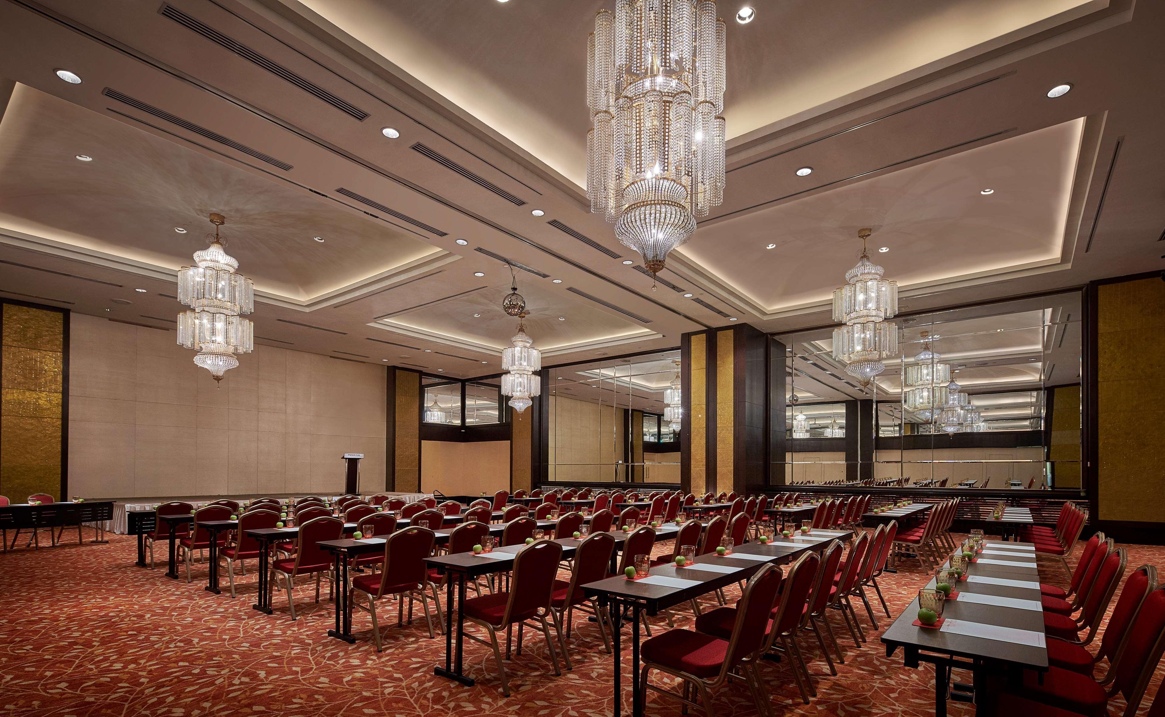 Parkroyal Penang Resort Batu Ferringhi Exterior photo The photo shows an elegant conference or meeting room. The space features several long tables arranged in a classroom style, with red chairs positioned around them. The room is well-lit with overhead chandeliers that add a touch of sophistication. Th