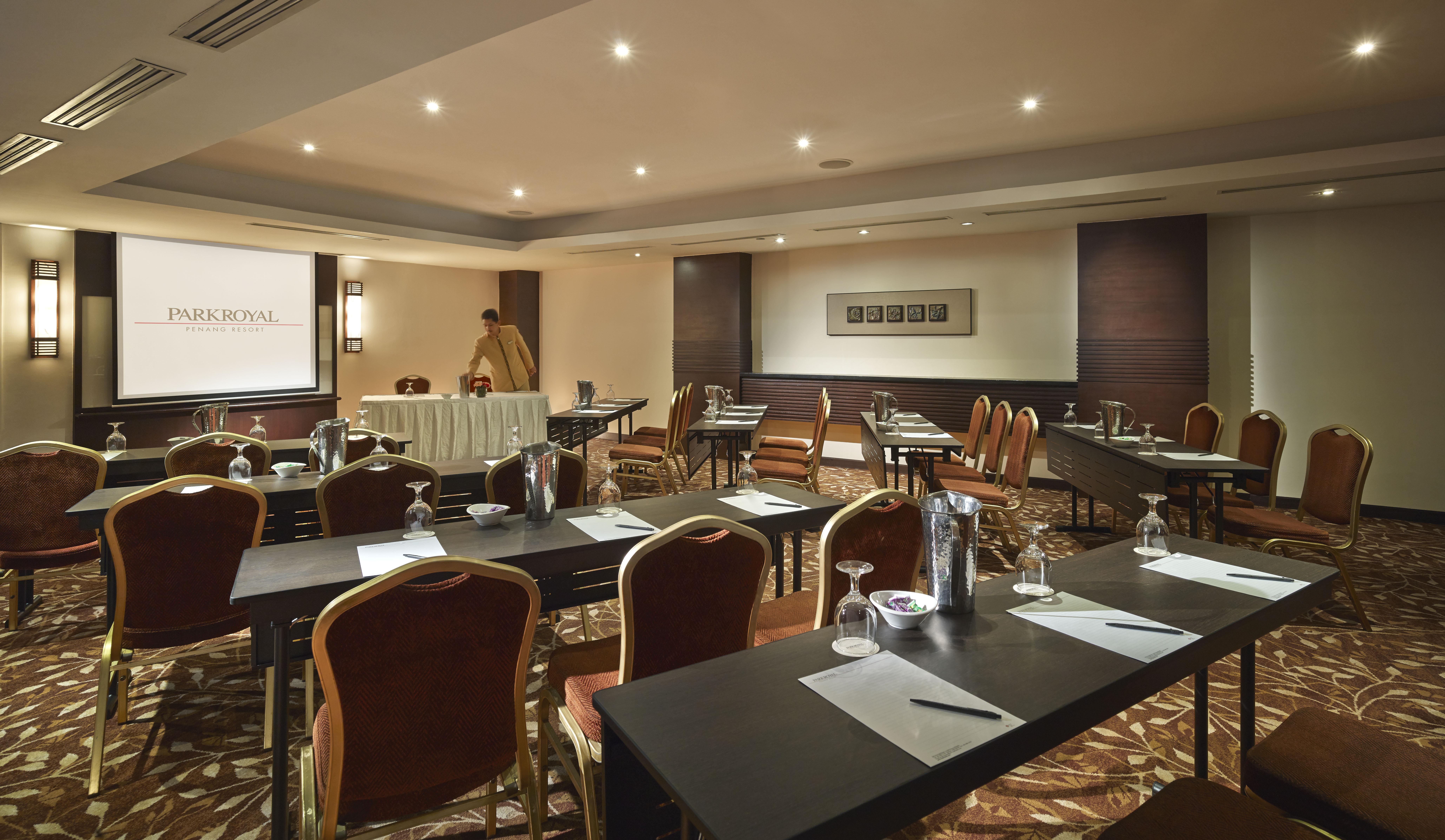 Parkroyal Penang Resort Batu Ferringhi Exterior photo The photo shows a conference room set up for a meeting or seminar. It features several tables arranged in a classroom or boardroom style, each equipped with chairs, stationery, glasses, and water pitchers. The room is well-lit with modern lighting an