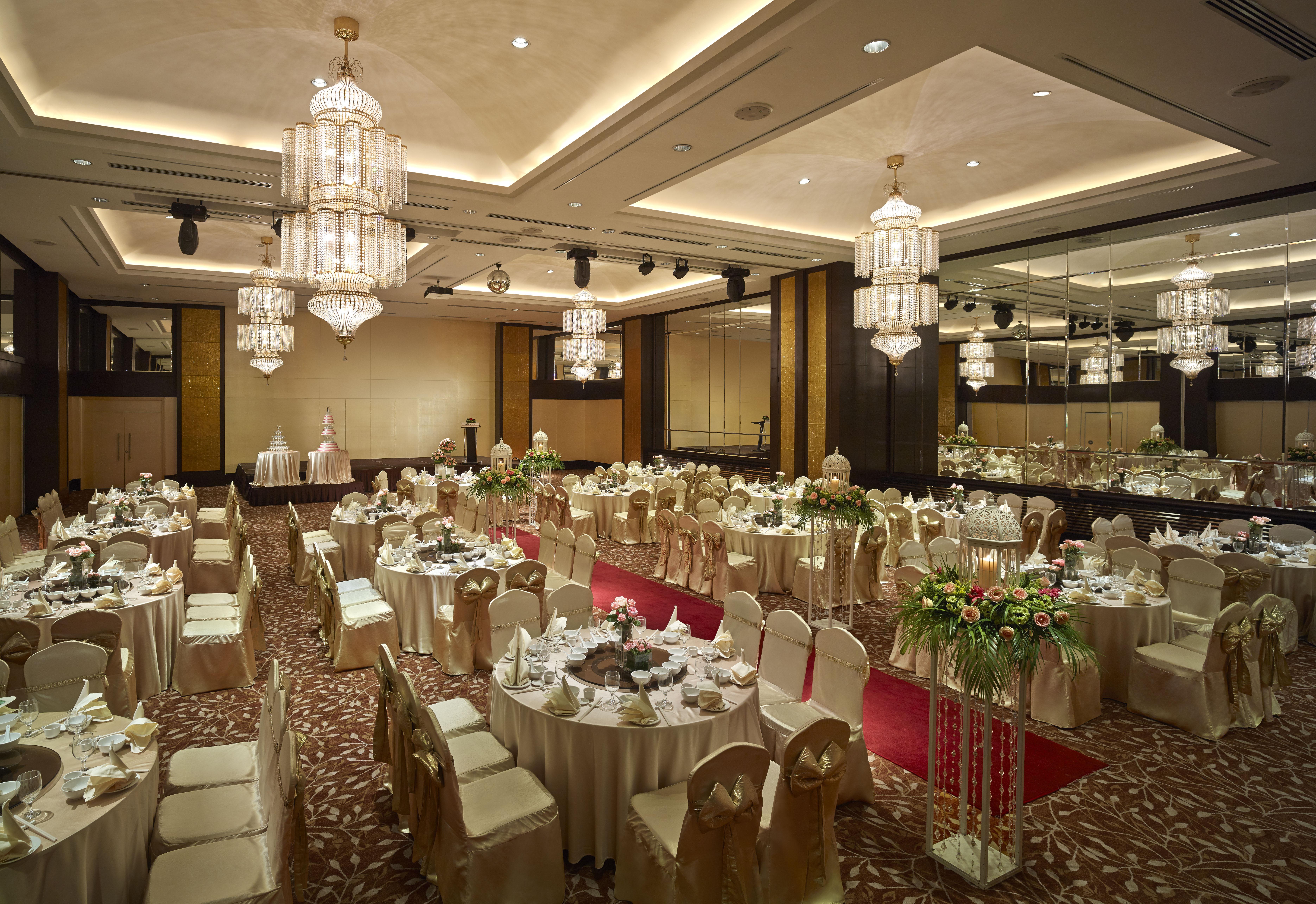 Parkroyal Penang Resort Batu Ferringhi Exterior photo The photo shows an elegant banquet hall set up for an event. The room features several round tables, each adorned with white tablecloths and decorative centerpieces. The chairs are mostly covered in gold fabric, adding a touch of sophistication. The 